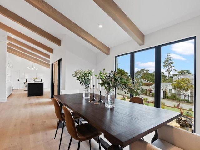 dining room featuring lofted ceiling with beams, a chandelier, and light hardwood / wood-style flooring