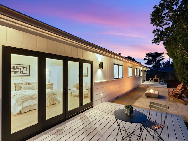 deck at dusk with french doors, a patio area, and a fire pit