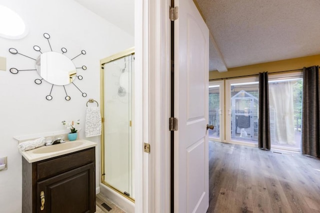 bathroom with walk in shower, vanity, wood-type flooring, and a textured ceiling