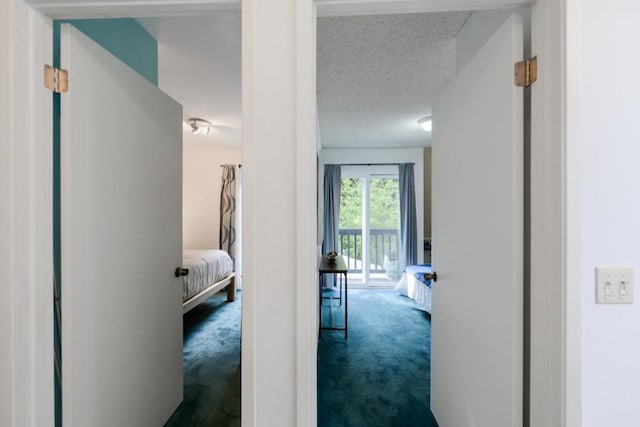 corridor featuring dark carpet and a textured ceiling