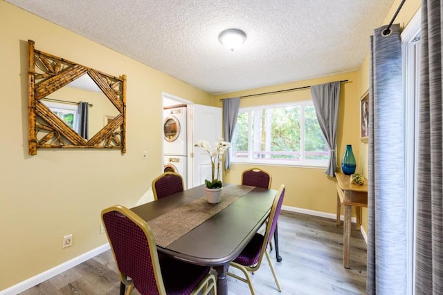 dining room featuring stacked washing maching and dryer, a textured ceiling, and hardwood / wood-style floors