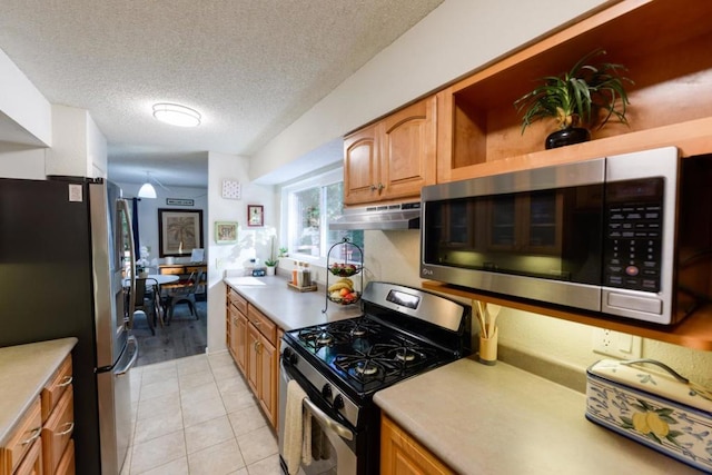 kitchen featuring appliances with stainless steel finishes, light tile patterned flooring, and a textured ceiling