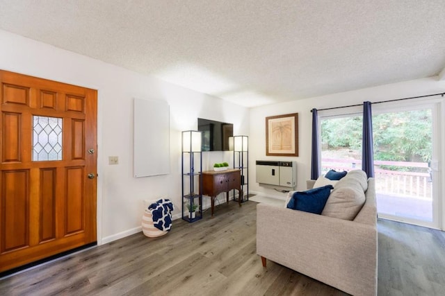 living room with heating unit, wood-type flooring, and a textured ceiling