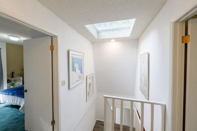 corridor featuring a skylight, a textured ceiling, and carpet flooring