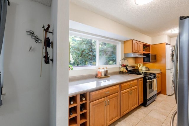 kitchen with a textured ceiling, light tile patterned floors, and appliances with stainless steel finishes