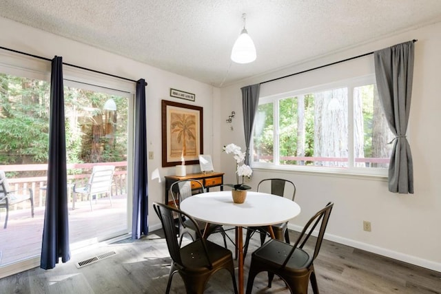 dining space with a textured ceiling and dark hardwood / wood-style flooring