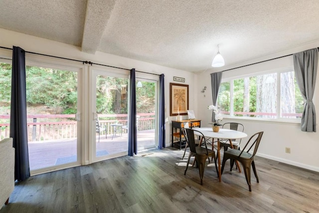 dining space with dark hardwood / wood-style floors, beamed ceiling, and a textured ceiling