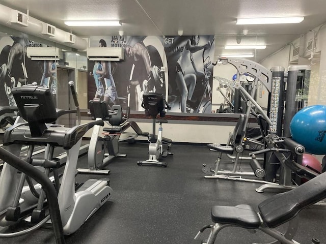 gym with an AC wall unit and a textured ceiling