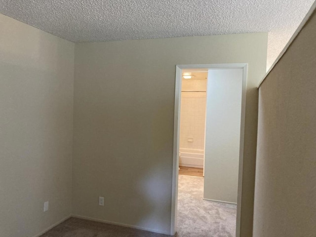 carpeted empty room with a textured ceiling