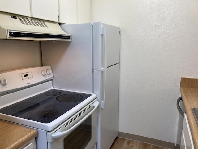 kitchen with white cabinets, light hardwood / wood-style floors, exhaust hood, and white range with electric stovetop