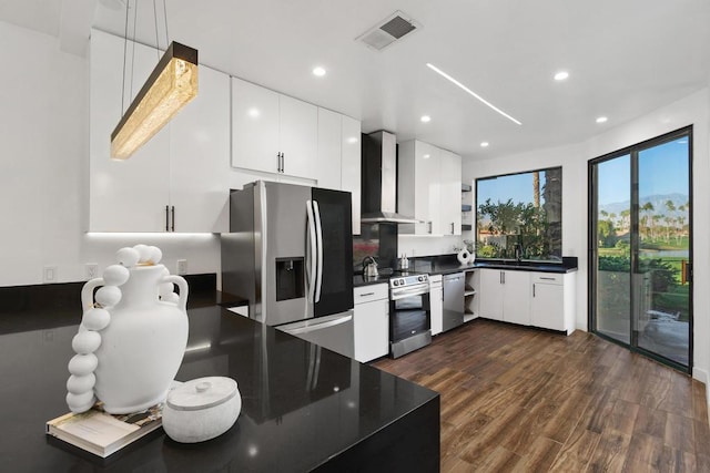 kitchen with appliances with stainless steel finishes, sink, white cabinets, dark hardwood / wood-style flooring, and wall chimney exhaust hood