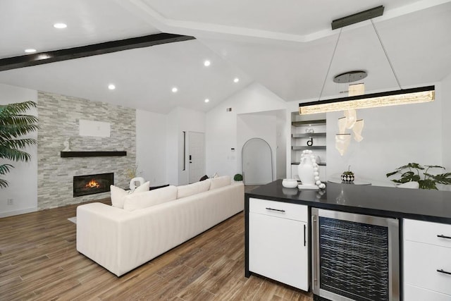 bar with white cabinets, a stone fireplace, hardwood / wood-style flooring, and wine cooler