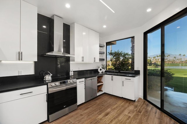 kitchen with appliances with stainless steel finishes, wall chimney exhaust hood, sink, and white cabinets