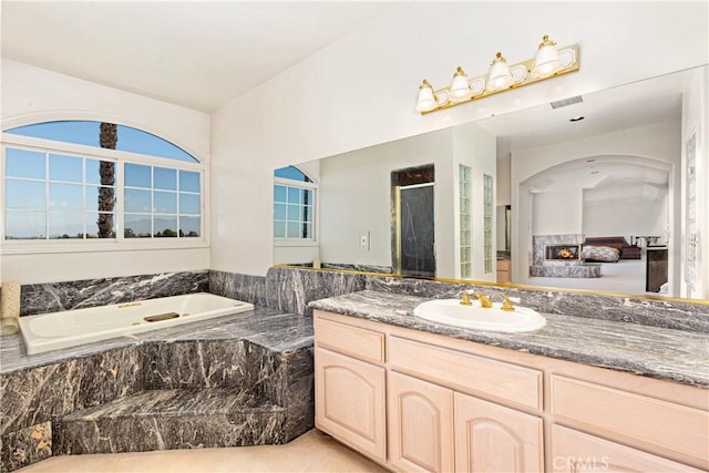 bathroom with tiled bath and vanity