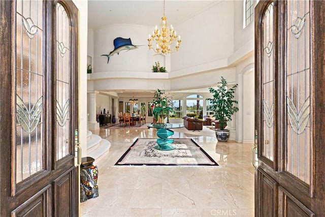 entrance foyer with ornate columns, a chandelier, and a high ceiling