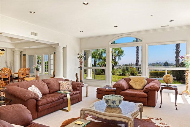 living room featuring plenty of natural light, crown molding, light carpet, and ornate columns