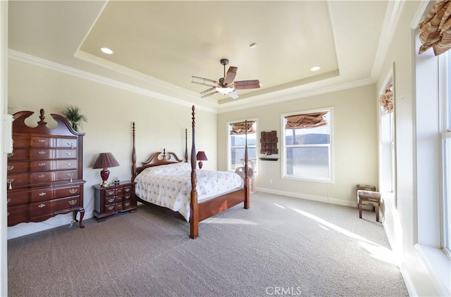 bedroom featuring ceiling fan, a tray ceiling, ornamental molding, and carpet floors