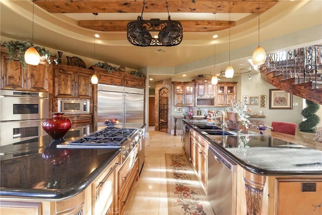 kitchen featuring light tile patterned floors, built in appliances, sink, and a tray ceiling