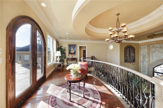 hallway featuring crown molding, a tray ceiling, french doors, dark hardwood / wood-style flooring, and a chandelier