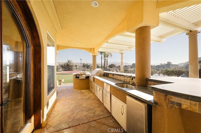 view of patio with a pergola, sink, a mountain view, and area for grilling