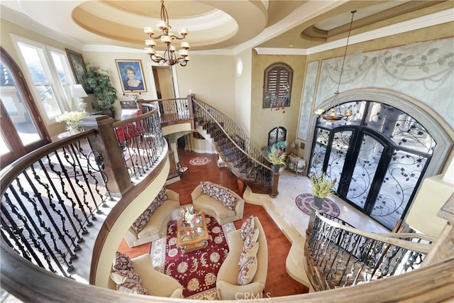 interior space featuring hardwood / wood-style floors, crown molding, a tray ceiling, french doors, and a chandelier