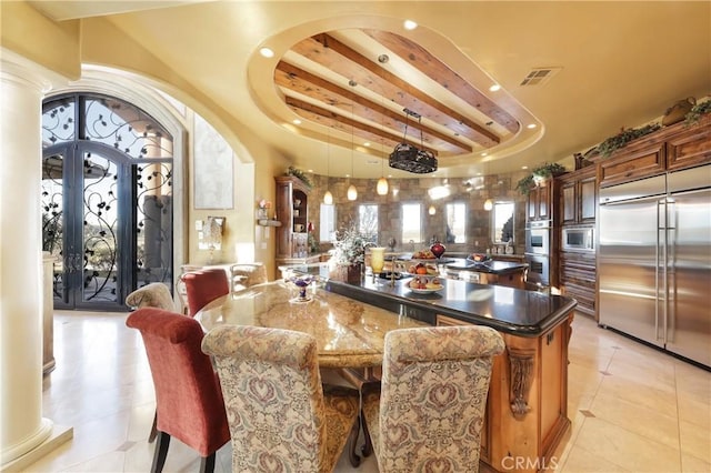 tiled dining area with decorative columns and a raised ceiling