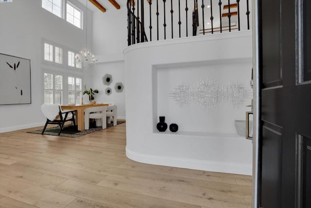 entryway featuring hardwood / wood-style flooring, a high ceiling, beam ceiling, and a notable chandelier