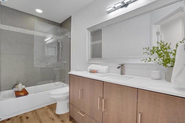 full bathroom featuring vanity, hardwood / wood-style floors, toilet, and combined bath / shower with glass door