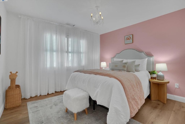 bedroom featuring an inviting chandelier and light wood-type flooring