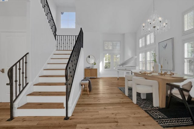 dining room featuring a high ceiling, a notable chandelier, and light wood-type flooring