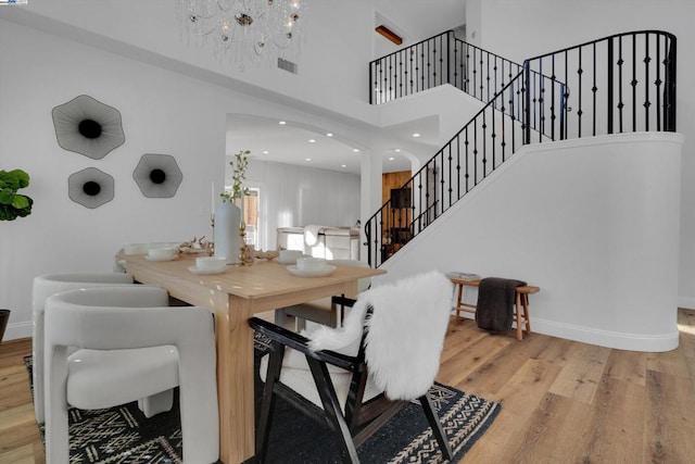 dining room with hardwood / wood-style flooring, a chandelier, and a high ceiling