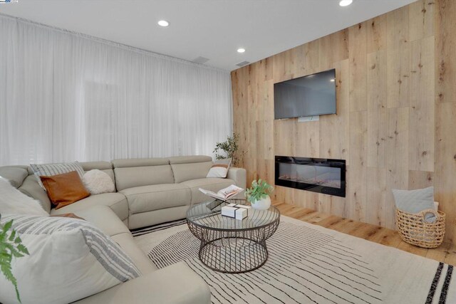 living room with wood walls and light wood-type flooring