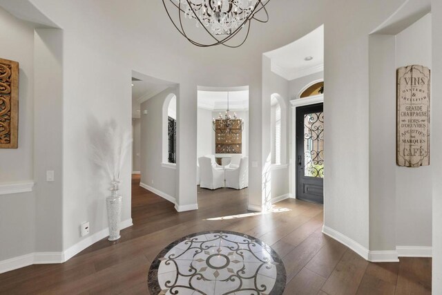 foyer entrance with ornamental molding, a chandelier, and dark hardwood / wood-style floors