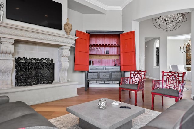 living room with light hardwood / wood-style flooring, crown molding, a notable chandelier, and a fireplace