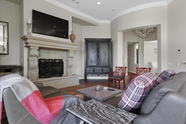 living room featuring dark wood-type flooring, a tile fireplace, crown molding, and a chandelier