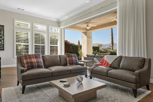 living room with ceiling fan, a mountain view, and ornamental molding