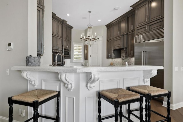 kitchen featuring a kitchen bar, kitchen peninsula, and built in appliances