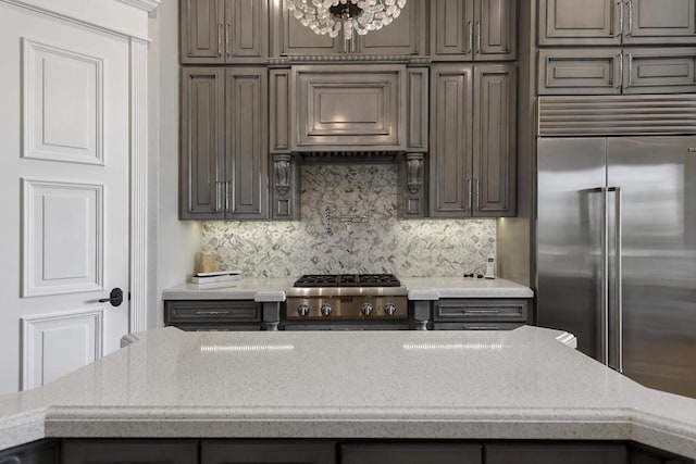 kitchen featuring stainless steel built in fridge, range, a chandelier, and tasteful backsplash