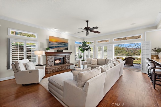 living room featuring a stone fireplace, a healthy amount of sunlight, and dark hardwood / wood-style floors