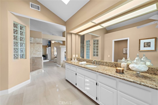 bathroom featuring ceiling fan, tiled shower, vanity, and lofted ceiling