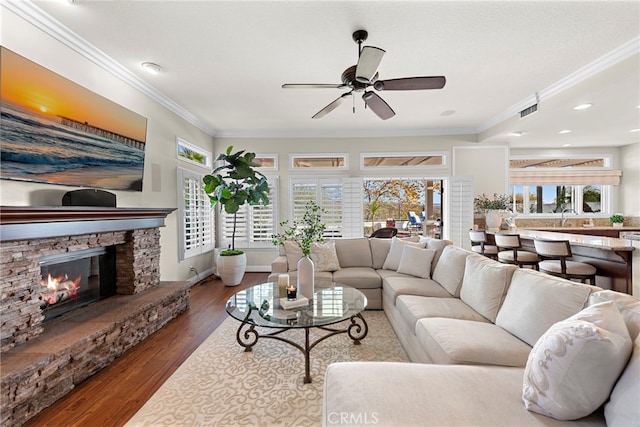 living room featuring a fireplace, ceiling fan, sink, hardwood / wood-style flooring, and crown molding