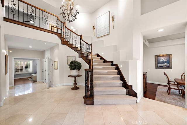 staircase featuring a towering ceiling, tile patterned flooring, and a notable chandelier