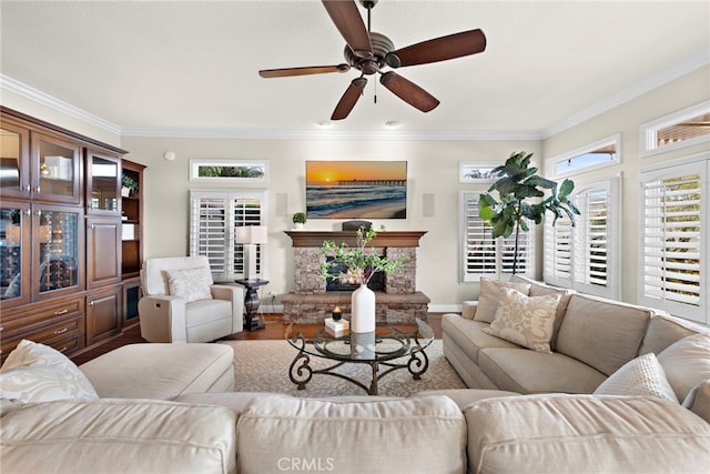 living room featuring a wealth of natural light, crown molding, and a stone fireplace