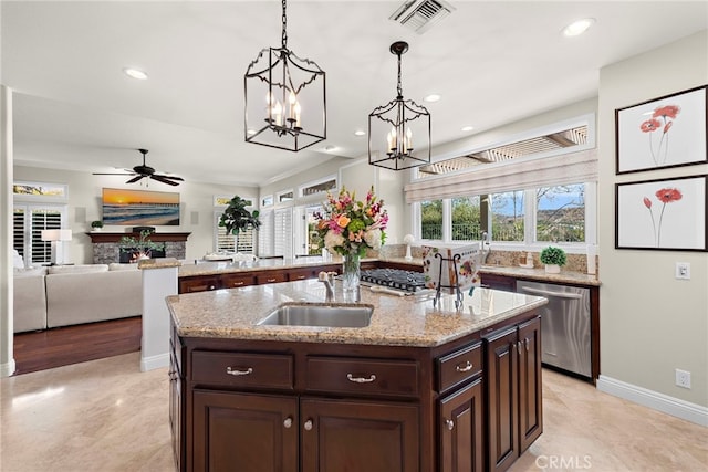 kitchen with a kitchen island with sink, a wealth of natural light, pendant lighting, and stainless steel appliances