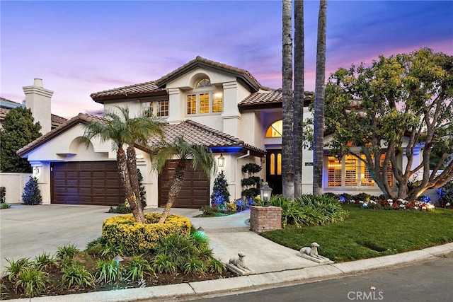 mediterranean / spanish-style home featuring a garage and a yard