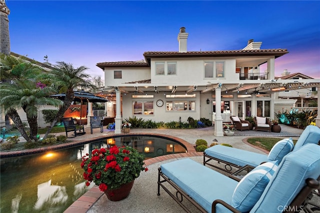 back house at dusk featuring a patio, an outdoor hangout area, and a pergola