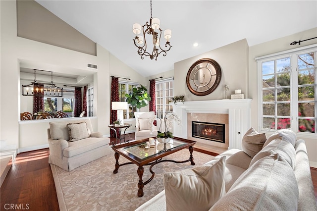 living room with high vaulted ceiling, hardwood / wood-style floors, and a notable chandelier