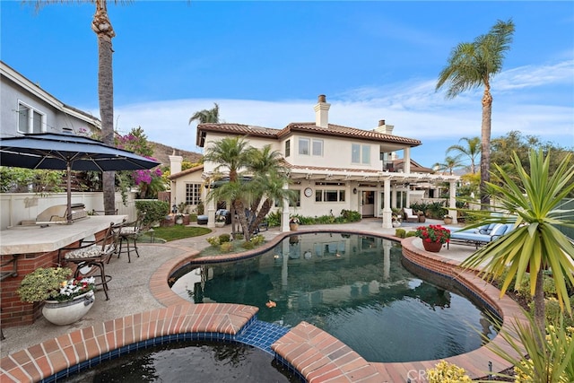 view of pool with a patio area, exterior kitchen, and a bar