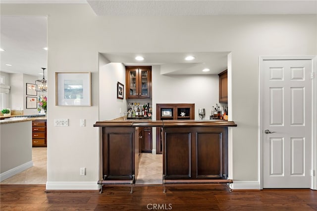 bar with pendant lighting, wood-type flooring, and dark brown cabinets