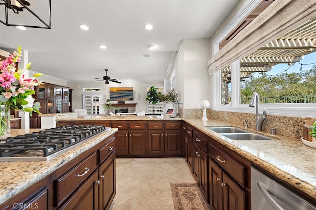 kitchen with dark brown cabinetry, stainless steel appliances, sink, light stone counters, and crown molding